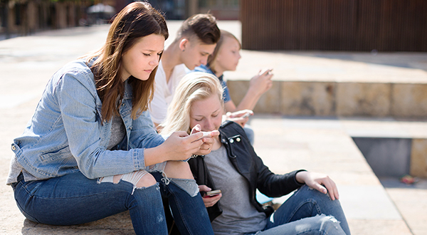 Schüler und Schülerinnen sitzen auf Treppe mit Handys in der Hand