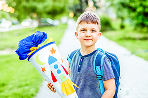 Junge im Alter von 7 Jahren hält eine Zuckertüte in der Hand und lächelt in die Kamera