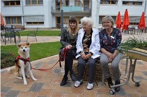 Ergotherapeutin Katja Zugehör, Bewohnerin Elfriede Geisenhainer und Leiterin Sabine Blask (vlnr) - Weiter im Bild ist Akiko - ein Therapiehund-Azubi © Holger Jakobi - Tag des Herrn