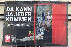 Einladung mittels Blow-up an der Hausfassade des Caritasverbandes