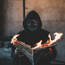 Hacker mit Maske und brennender Zeitung