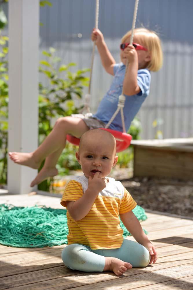 Kind auf der Schaukel mit Baby